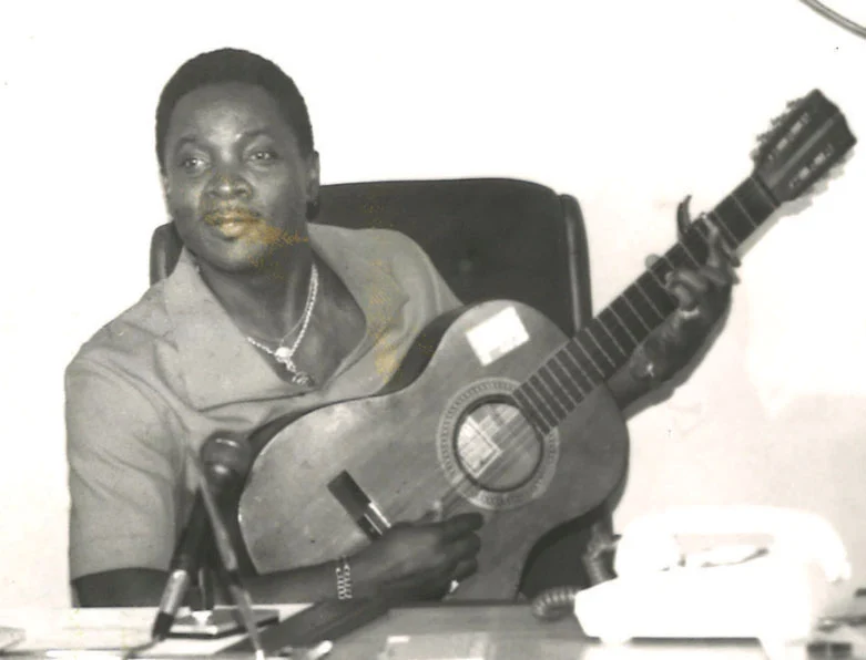 The Mighty Sparrow seated with an acoustic guitar